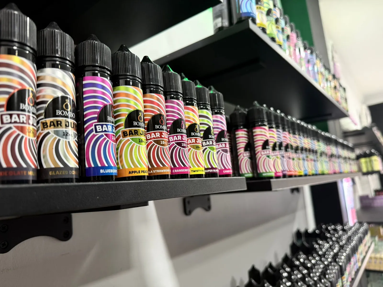 Pared de la tienda de vapeo MASVAPE en Málaga con las baldas llenas de botellas y cajas