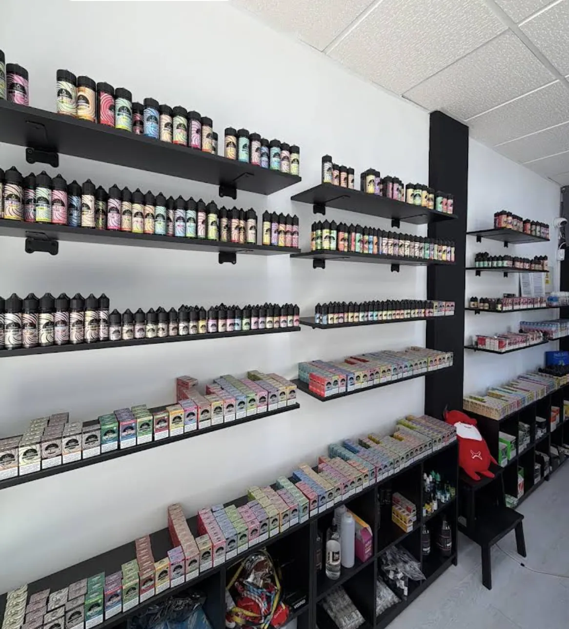 Pared de estanterías de MASVAPE con líquidos y cajas ordenados por baldas